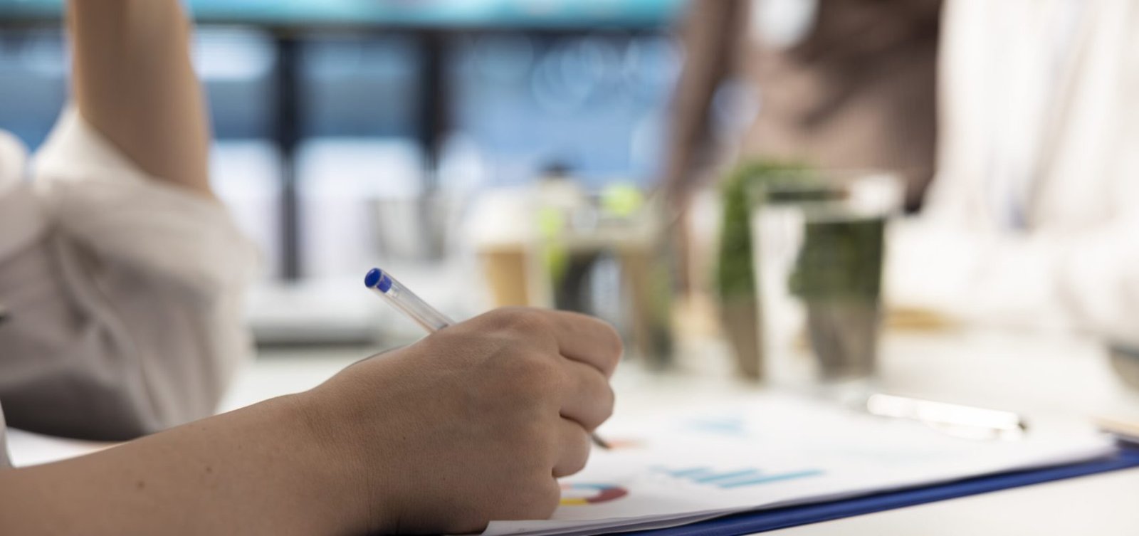 Marketing manager evaluating sales and profit within infographics data, writing a financial projection with the staff in a meeting. Coworkers sharing insight in a briefing conference. Close up.